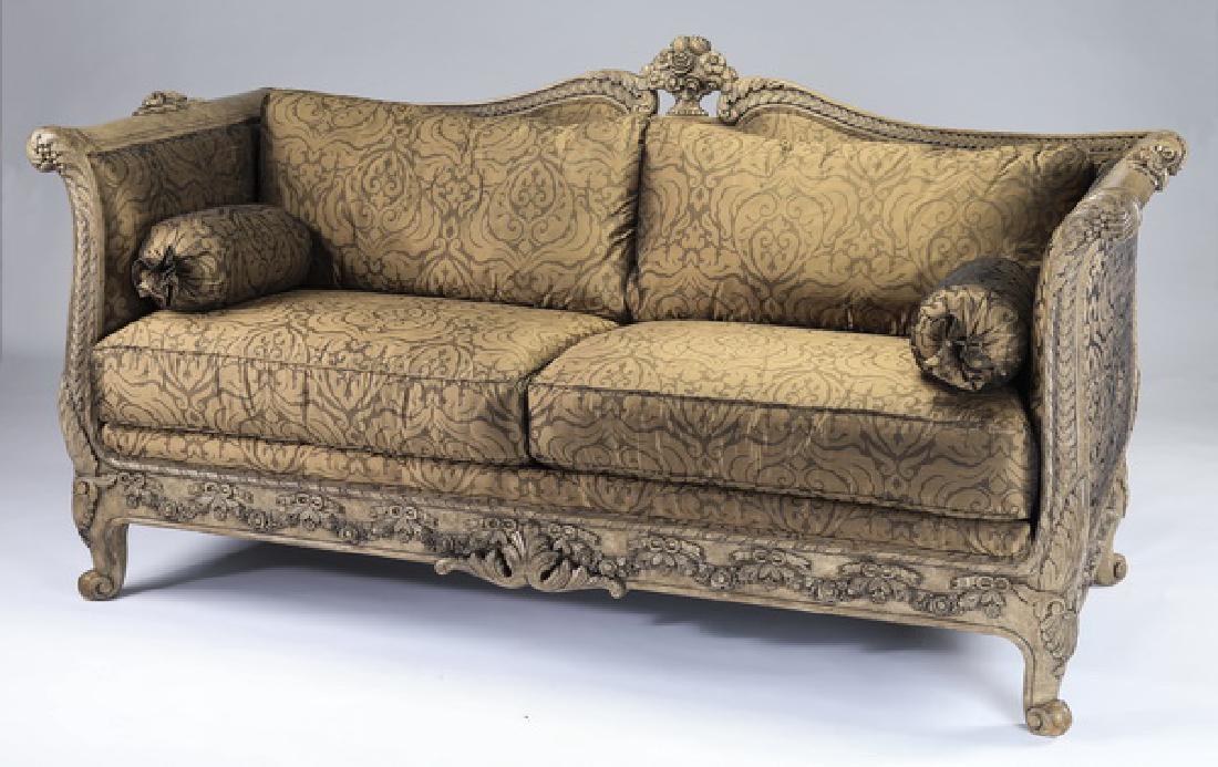 Italian carved & parcel gilt sofa upholstered in silk: Italian carved and parcel gilt sofa in the Regency taste, having a double arched crest rail centering a carved urn of flowers flowing into scrolled arms, flanking a back and seat with loose cushions u