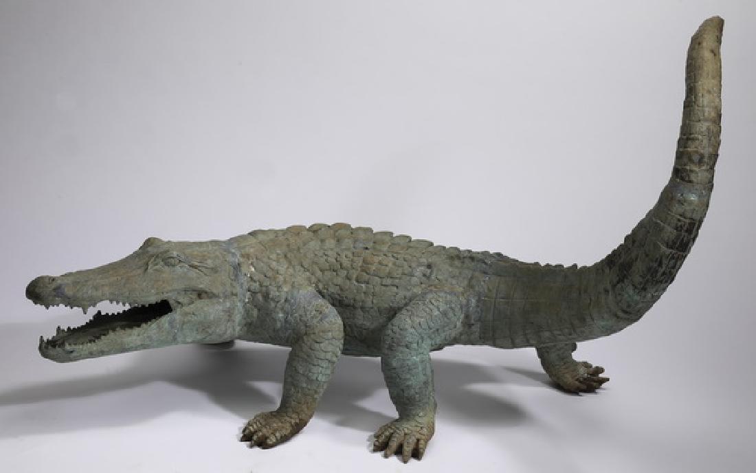 Patinated bronze sculpture of an alligator, 42"l: Patinated bronze sculpture of an alligator, depicted walking with its tail in the air and open jaws, 28"h x 42"l x 27"w.