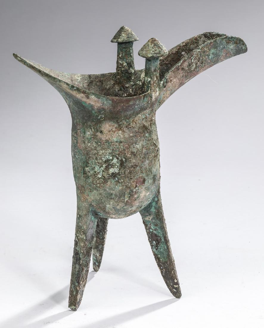Chinese bronze Jue, possibly Shang Dynasty, 9"h: Chinese bronze Jue or ritual wine vessel, possibly Shang Dynasty, 1766- 1046 BC, having opposing double spouts, one side surmounted by a pair of conical capped posts, above a deep 'U'-shaped body with