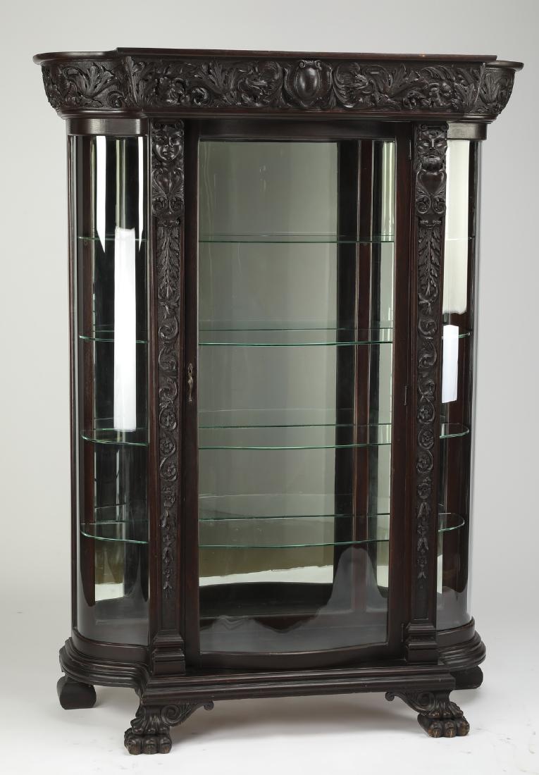 Early 20th c. American carved oak & glass vitrine: American Renaissance Revival carved oak vitrine, early 20th century, having a carved cornice with a central cabochon flanked in scrollwork, above a central glass cabinet door opening to a mirrored bac