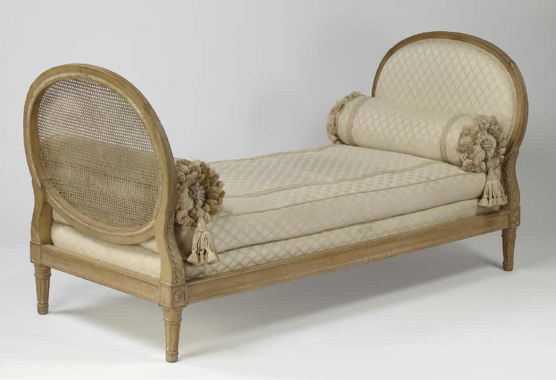 Cerused oak daybed in the Louis XVI taste, 73"l: Cerused oak daybed in the Louis XVI taste, mid 20th century, having a bench seat or mattress covered in cream diamond upholstery flanked by an oval upholstered headboard and an oval caned footboard, t