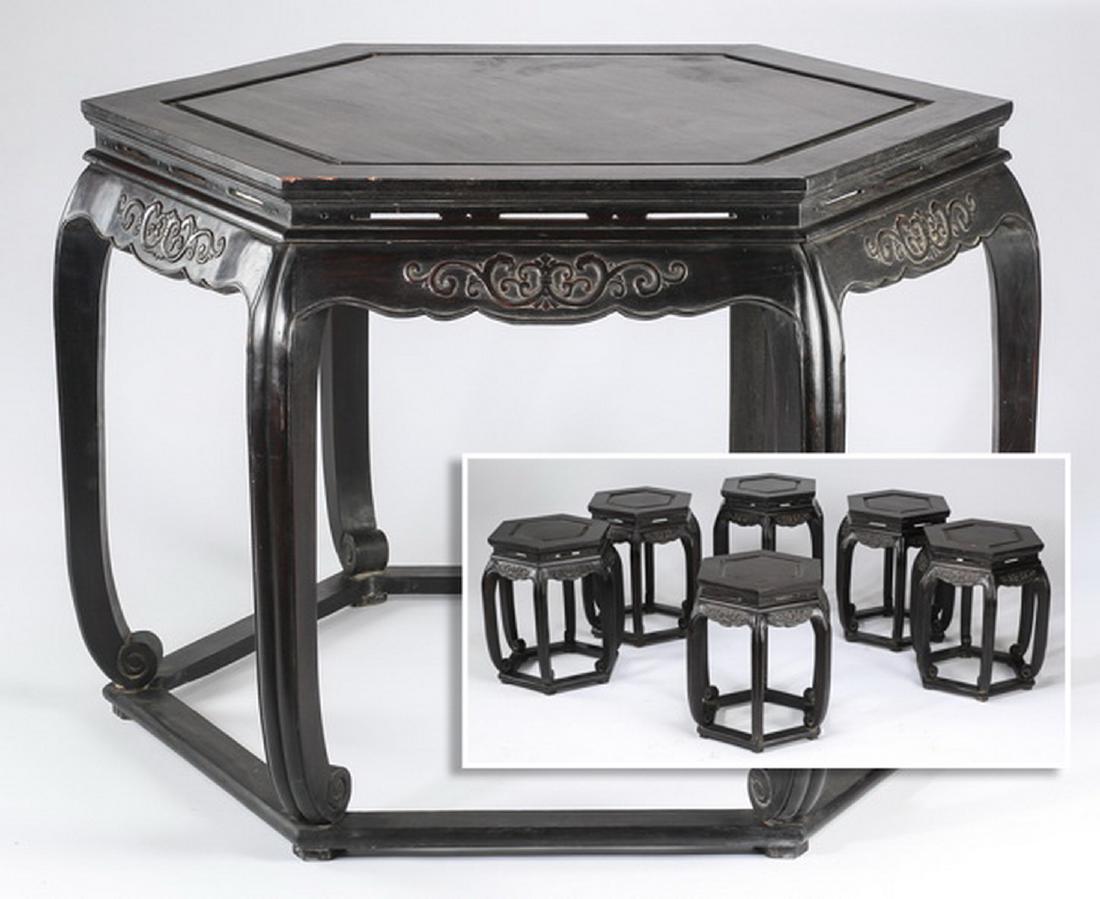 Chinese ebonized tea table and six stools: Chinese carved and ebonized tea table supported by six inswept legs ending in scroll feet, conjoined by base stretchers, 33"h x 47"w, accompanied by six matching stools, 19.5"h x 15.5"w.