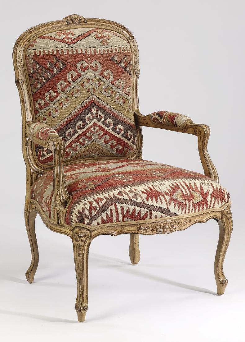 Louis XV-style kilim upholstered armchair: Louis XV style armchair, the carved frame centering a floral cartouche leading to scroll arm terminals with kilim upholstered manchettes, above the kilim upholstered seat surmounting the foliate apron