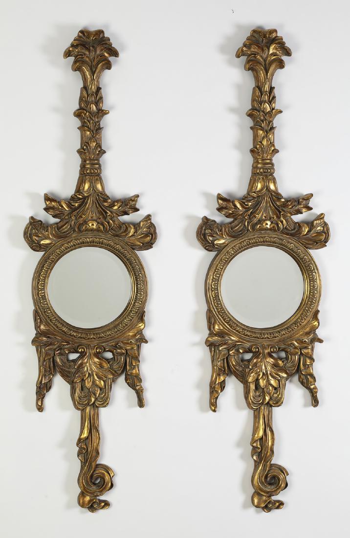 (2) Neoclassical inspired garland mirrors 52"h: Pair of Neoclassical inspired mirrors, executed in composition material with an antique gold finish, each having a floral garland suspending a circular mirror, terminating to a swaged and draped ribbo