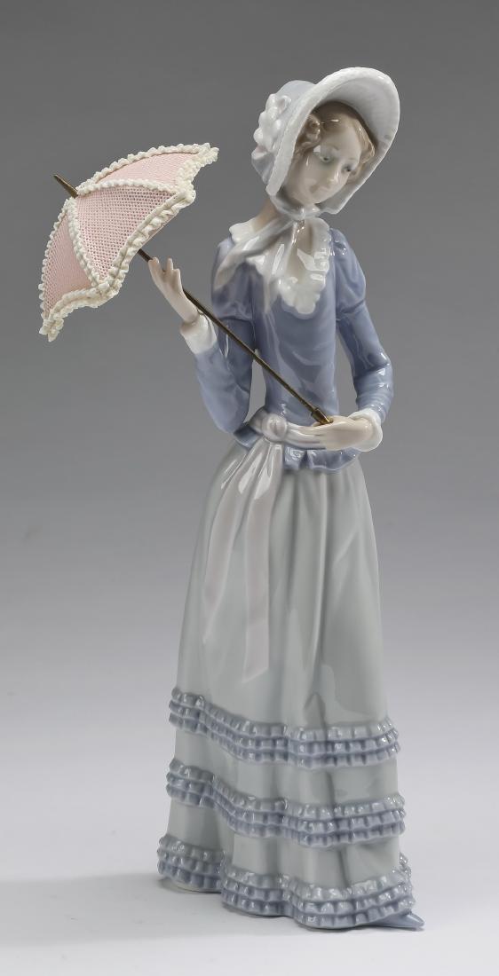 Retired Lladro 'Little Lady' porcelain figure, 13"h: Retired Lladro 'Little Lady' porcelain figure, depicting a girl dressed in the garb of the late 19th century and wearing a bonnet while holding a delicate pierced pink parasol, model number 4879, desi