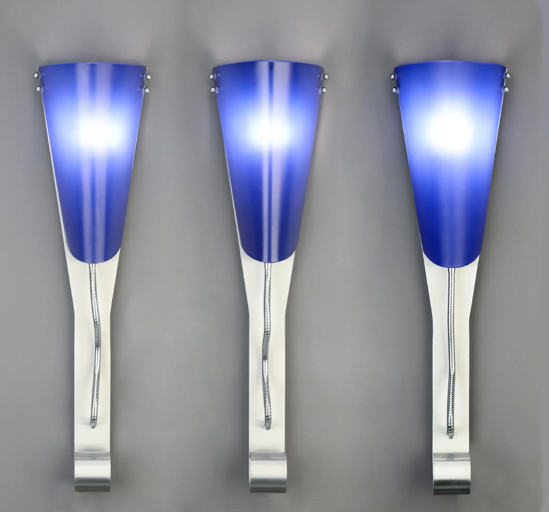 (3) Contemporary cobalt blue glass wall sconces: Group of (3) brand new contemporary stainless steel wall sconces, each having a flared cobalt blue glass shade surmounting a scrolling standard, 24"h x 7"w x 4.5"d.