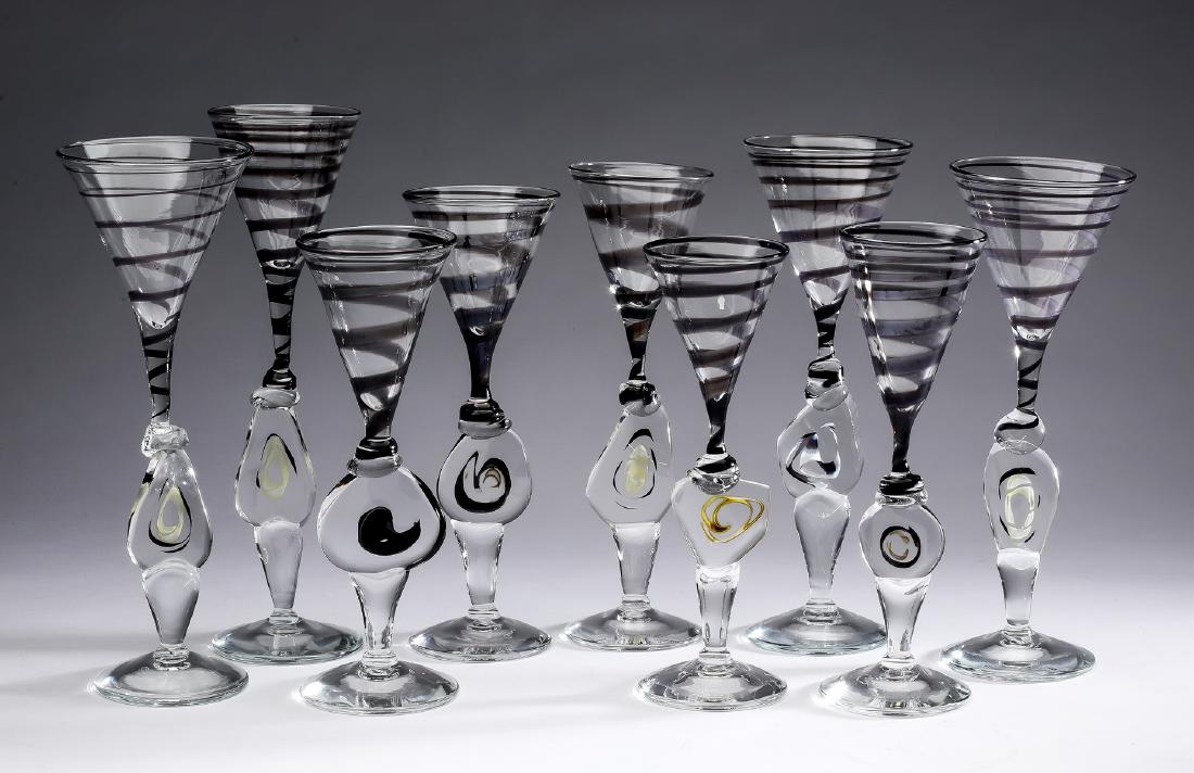 (9) Hand blown Cam Langley Memphis style flutes, 11"h: Nine hand blown, signed, studio glass flutes in the Memphis style by Cam Langley, (American 1948-2013), having trumpet form bowls in clear glass with smoke spiral bands, rising on flattened free form 