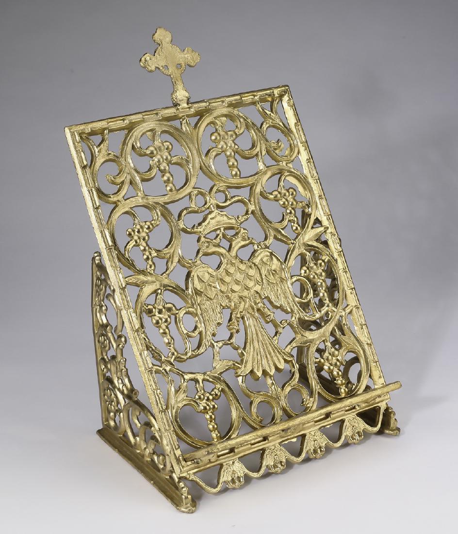 Cast gilt metal missal stand with double headed eagle: Missal stand, early 20th century, executed in cast gilt metal, centering a double headed eagle surrounded by scrolling ornamentation and clusters of grapes and topped with a Byzantine cross, 15"h x 11