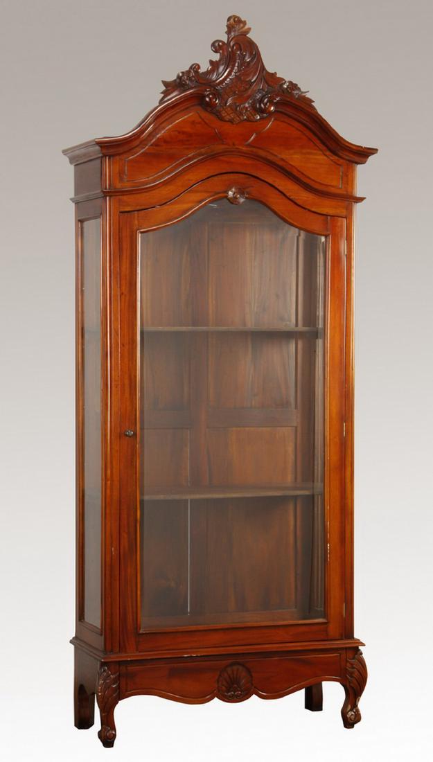 Carved Rococo style mahogany vitrine, 101"h: Carved mahogany Rococo style vitrine, the asymmetrical carved acanthus leaf crest surmounting a beveled glass door and glass side panels over a serpentine apron terminating in cabriole legs, 101"h x 4