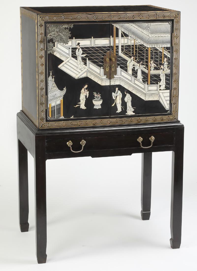 Chinoiserie style ebonized coromandel cabinet: Chinoiserie style ebonized coromandel cabinet, the upper case centering two carved doors depicting a scene of beauties in a court pavilion amidst pagodas and trees, enclosed by a leiwen border and ope