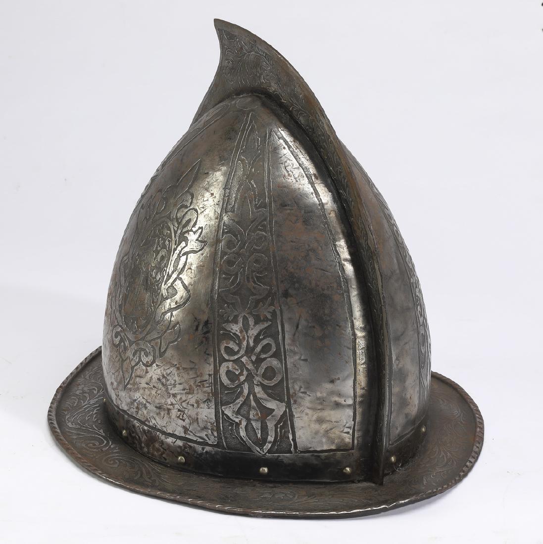 Renaissance style replica morion helmet: Renaissance style patinated metal replica morion helmet, having a dome-shaped form with comb and flat brim, displaying panels of etched foliate patterns and a cartouche depicting a female figure holdi