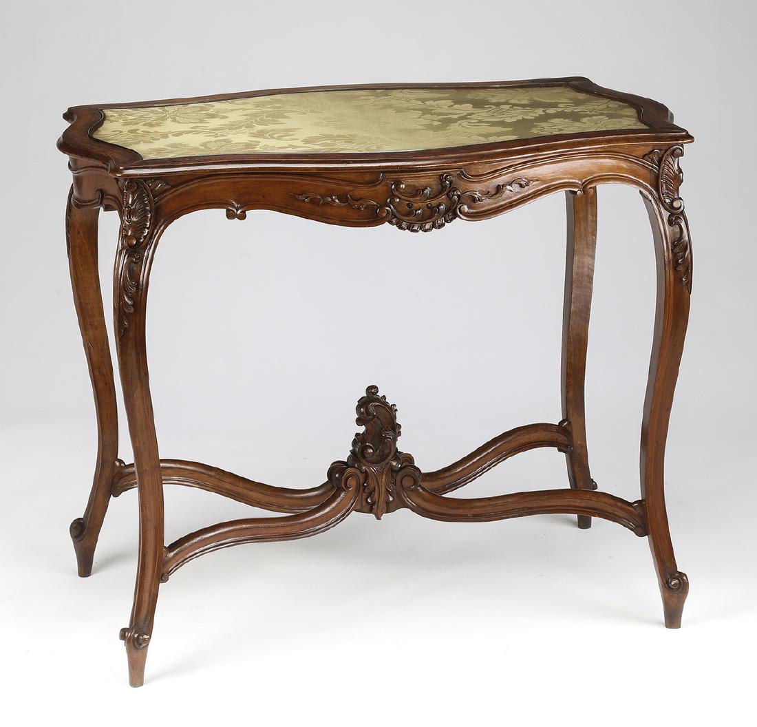 19th c. French Rococo style walnut side table: French Rococo Revival walnut side table, late 19th century, having a turtle shape top with gold silk damask captured under glass, above a shaped apron carved with foliate 'C' scrolls, the whole rising