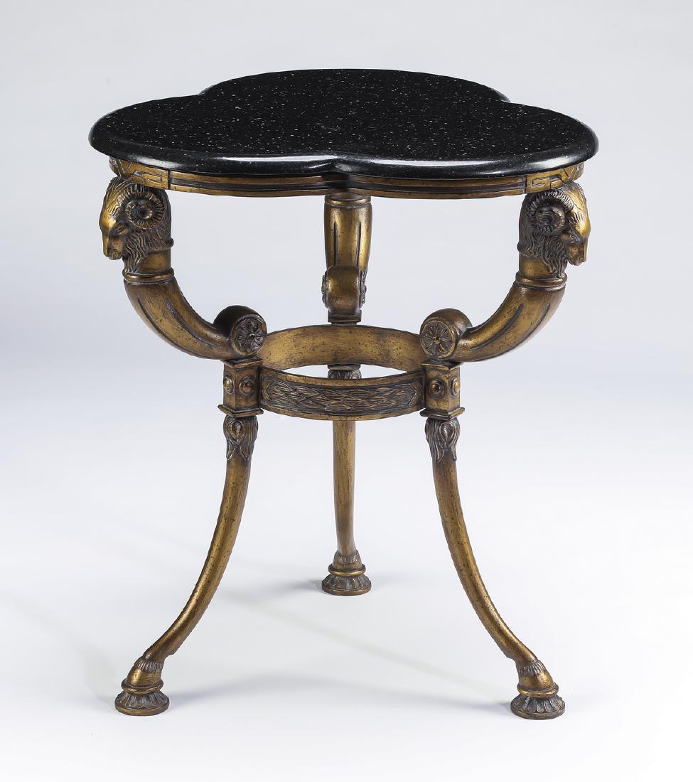 Bronze gueridon style table with trefoil granite top: Bronze gueridon style table, having a trefoil granite top above gilt ram's heads continuing to curving legs joined by a foliate ring terminating to hooved feet on pads, 25"h x 21.5"w x 21.5"d.
