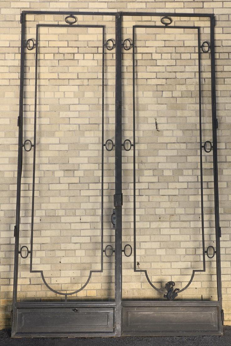 Ornamental iron double doors, 128"h x 79"w: Ornamental iron double doors, having an arched frame connected by ovals to an outer frame, with a rectangular skeleton key escutcheon above the iron handle, 128.25"h x 79"w x 1.75"d. (Lacking glass pa