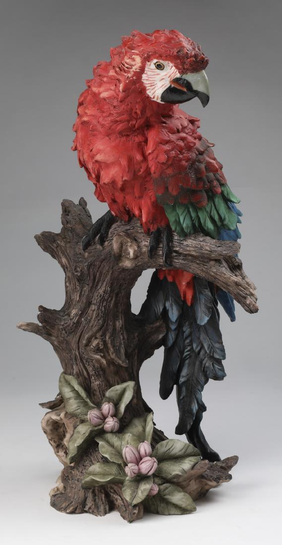 Wildlife sculpture of vibrant parrot in a tree: Wildlife sculpture executed in composition material, depicting a vibrant parrot perched on a tree branch with small blooming flowers, 19"h x 11.5"w x 9"d.