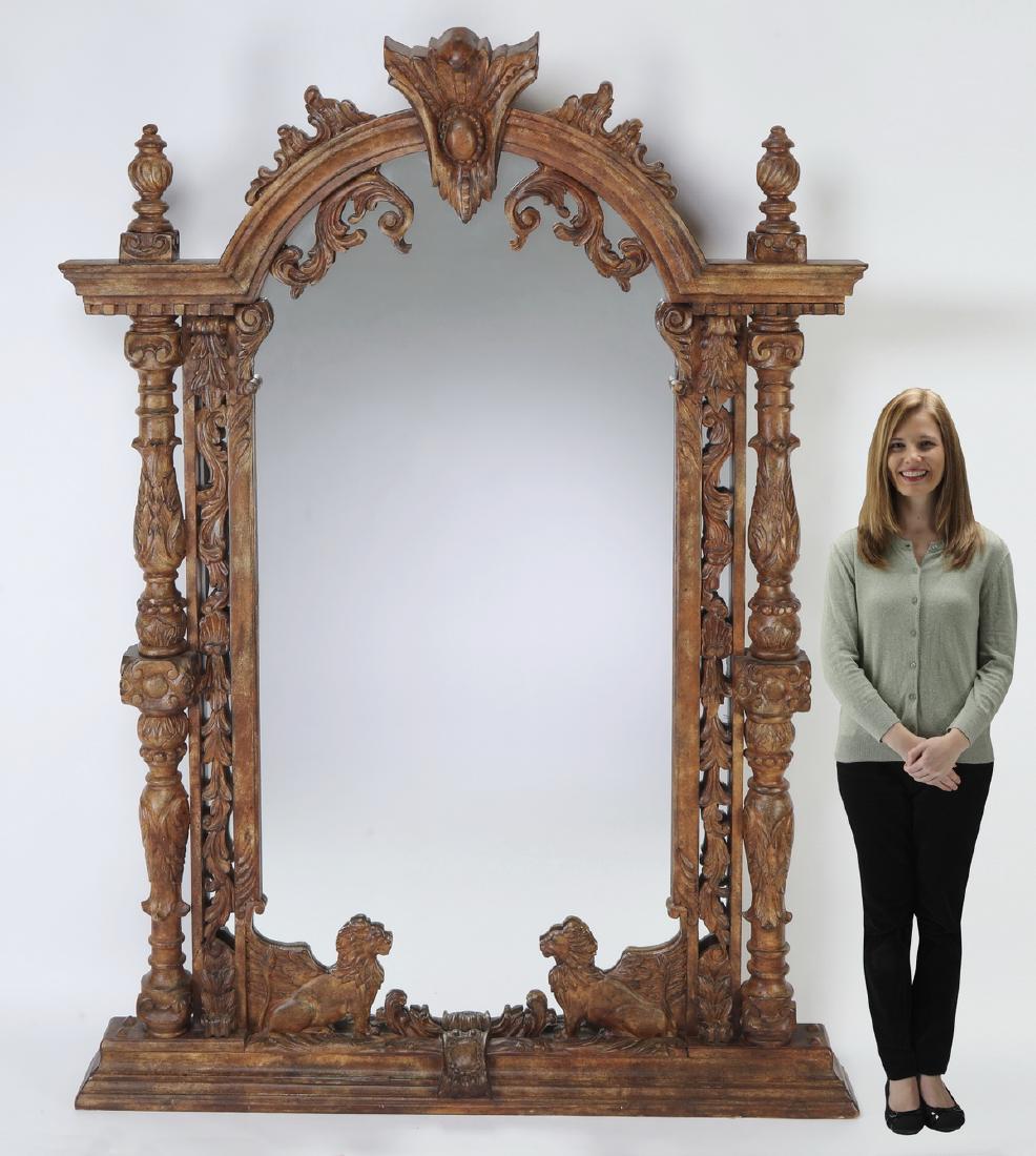 Monumental carved mirror w/ winged lions: Monumental Renaissance Revival style mirror, executed in carved and gessoed wood with an antiqued finish, having an arched crest centering a keystone with a double cabochon flanked by acanthus scrollw