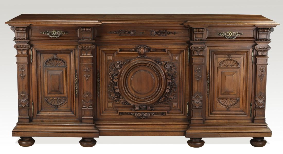 19th c. French walnut buffet with carved oak leaves: French Renaissance Revival walnut buffet, late 19th century, having a rectangular top with a breakfront, over a conforming trifurcated case with three frieze drawers over three doors, the main door ce