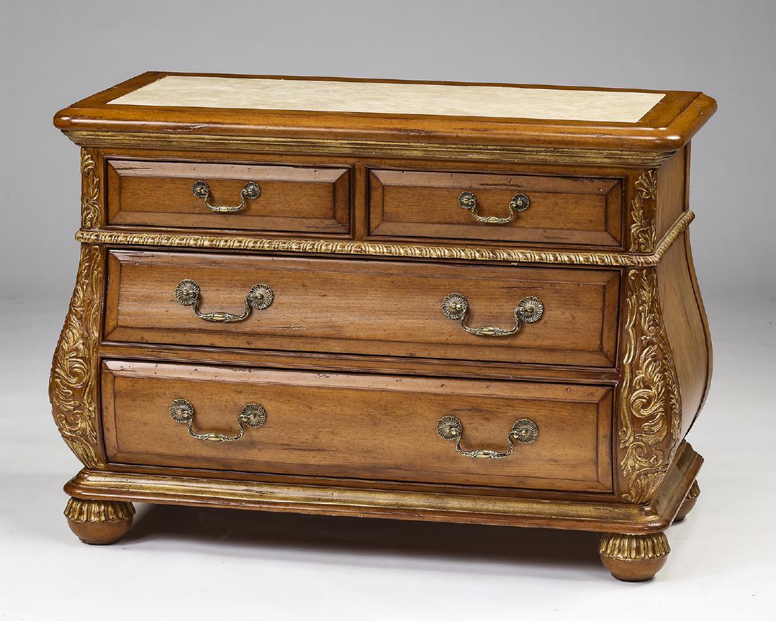 Marge Carson marble top bombe' commode: Marge Carson light mahogany bombe' commode, having an inset tan marble top above a bombe cabinet with two over two drawers flanked by relief carved and gilded acanthus scrollwork, the whole resting on