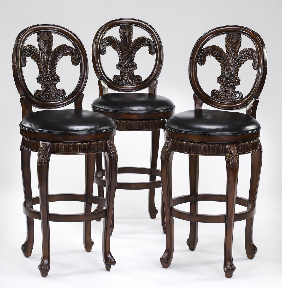 (3) Carved mahogany swivel barstools in leather: Set of three Sheraton style barstools, executed in mahogany and black leather, each having an oval back centering a carved Prince of Wales feather splat, above a circular black leather swivel seat, th