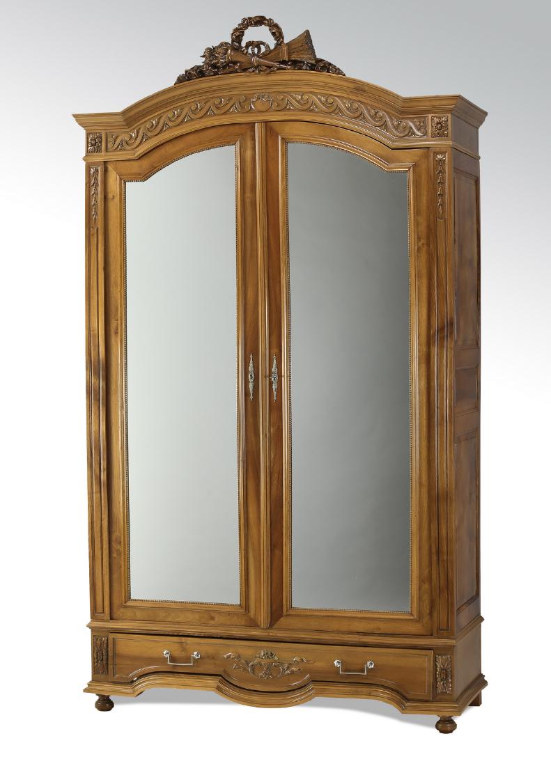 19th c. French carved walnut mirrored armoire, 96"h: French Neoclassical style walnut armoire, 19th century, having a Neoclassical style carved bow and arrow trophy crest surmounting an arched carved meander frieze and two arched doors with beveled mirr