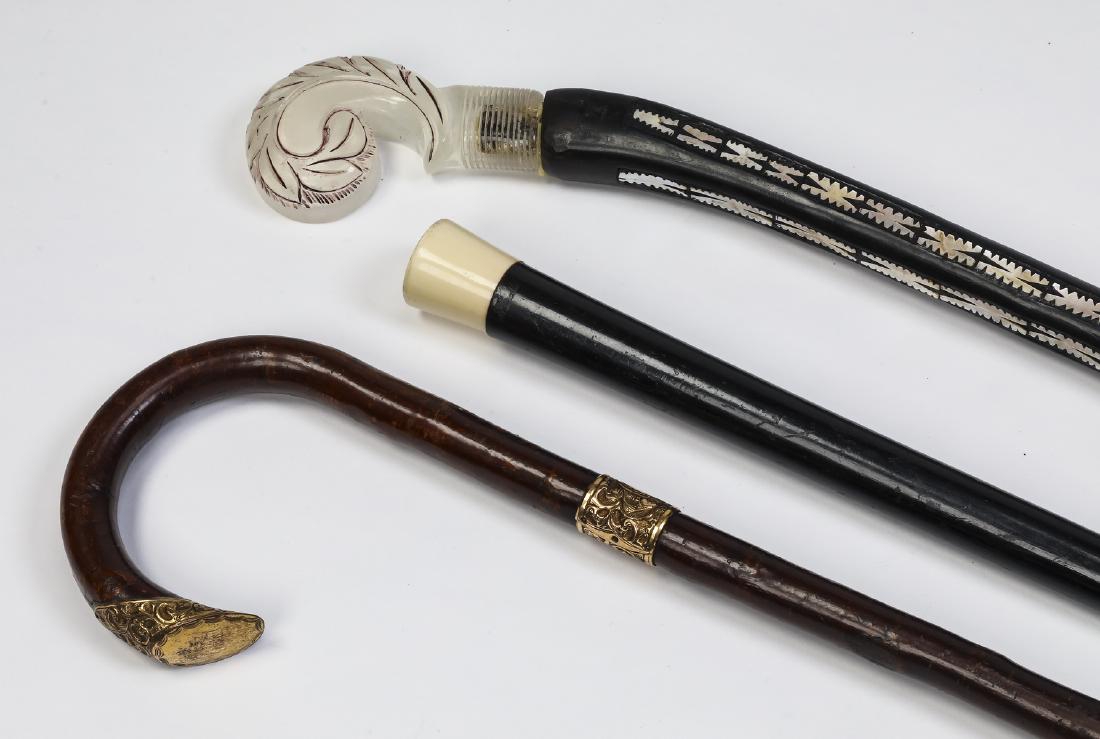 Group of (3) walking sticks including mother of pearl: Group of (3) walking sticks comprised of (1) ebony walking stick, having an ivorine knob handle with incised black monogram 'A.H', over a straight shaft terminating to a horn ferrule, 36"l; (1) mother