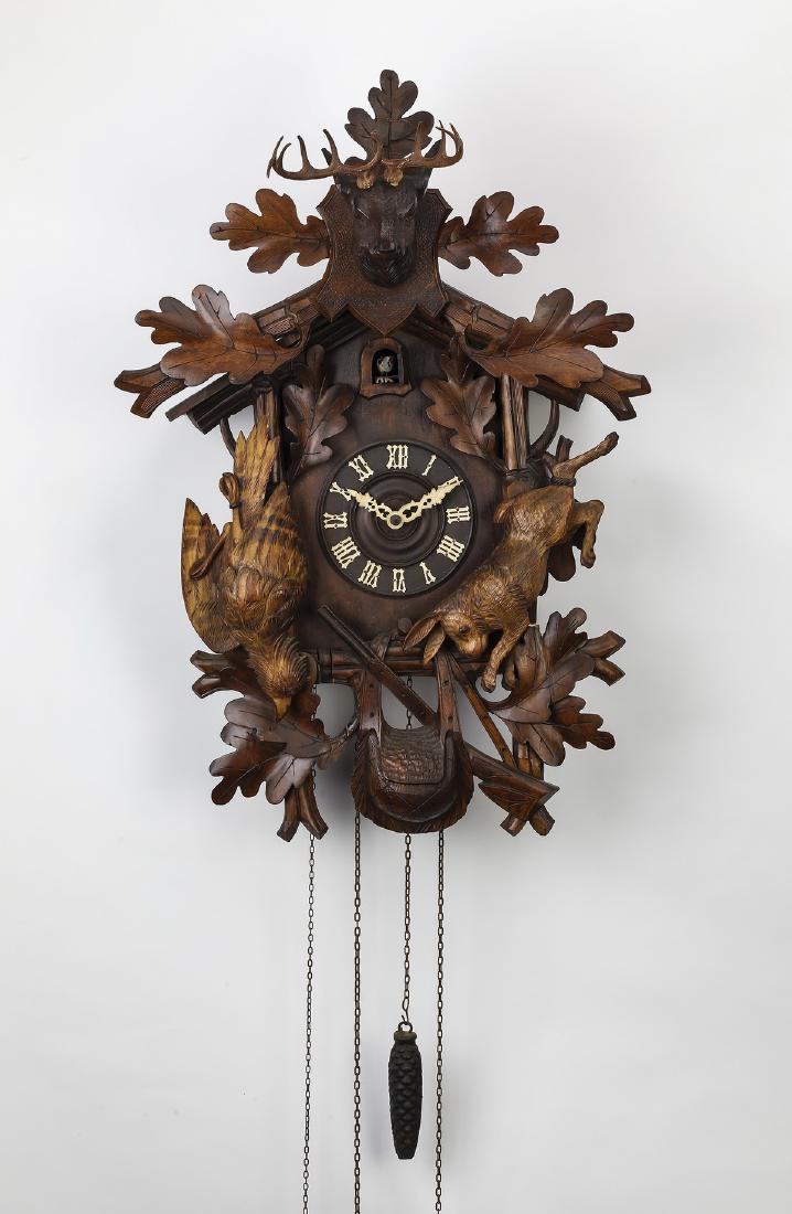 Black Forest walnut cuckoo clock, 26"h: Black Forest carved walnut cuckoo clock, 20th century, having an oak leaf finial and carved buck trophy head, over a birdhouse case centering a cuckoo door, above a circular clock face with white Roma