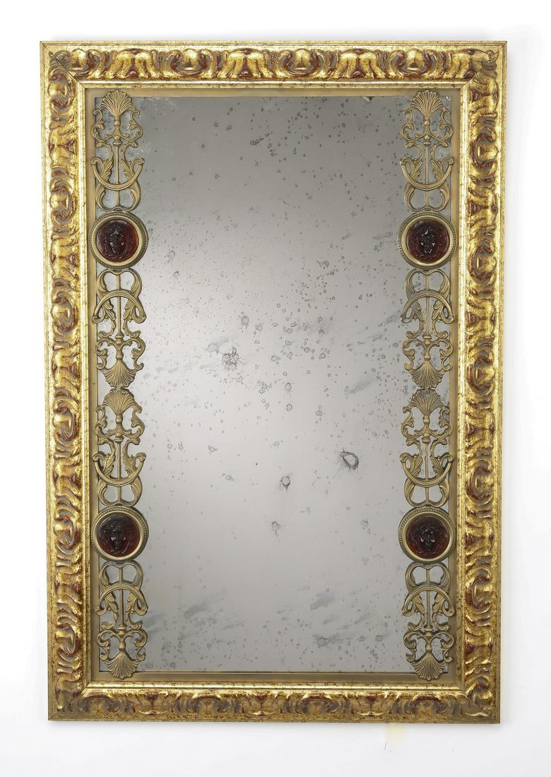 Italian gilded mirror with Murano glass accents: Italian gilded and carved mirror with Murano glass accents, having an antiqued rectangular mirror flanked by bronze scrollwork mounts, each inset with burgundy Murano glass Medusa masks, the whole bor