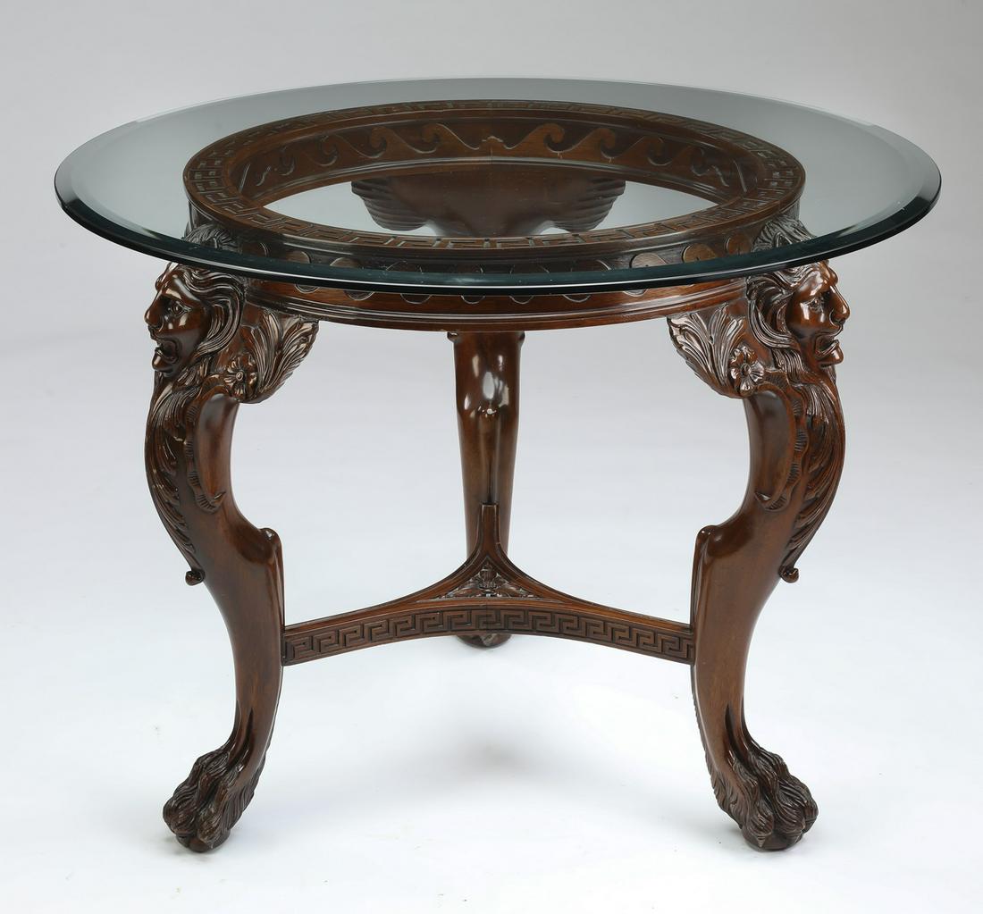 Maitland-Smith style mahogany center table: Maitland-Smith style mahogany and glass center table, having a round glass top with a double beveled edge resting on a mahogany ring relief carved with Greek key and wave bands, rising on cabriole leg