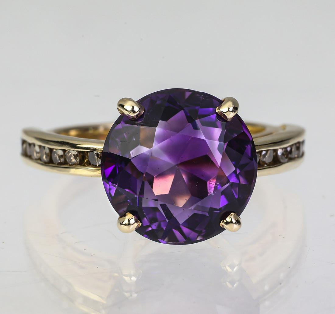 Amethyst, sapphire, and 14k yellow gold ring: Amethyst, sapphire, and 14k gold ring, centering an approximately 5.5 carat round brilliant cut amethyst flanked by round brilliant cut sapphires channel set in the shoulders of the mount, size 6. **P