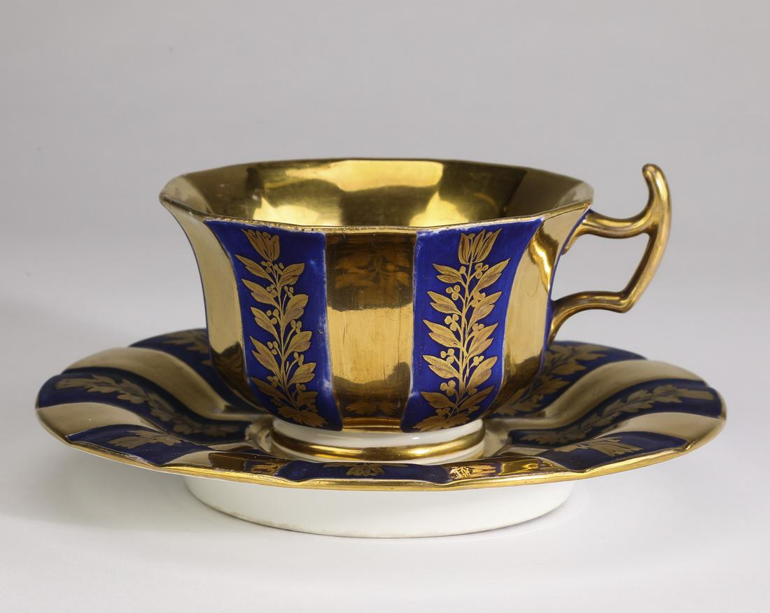 19th c KPM porcelain Biedermeier teacup & saucer: Early 19th century KPM porcelain Biedermeier teacup and saucer, comprising: (1) teacup with a flared rim decorated in alternating gilded stripes and cobalt stripes with gilded foliate vine motifs, hav