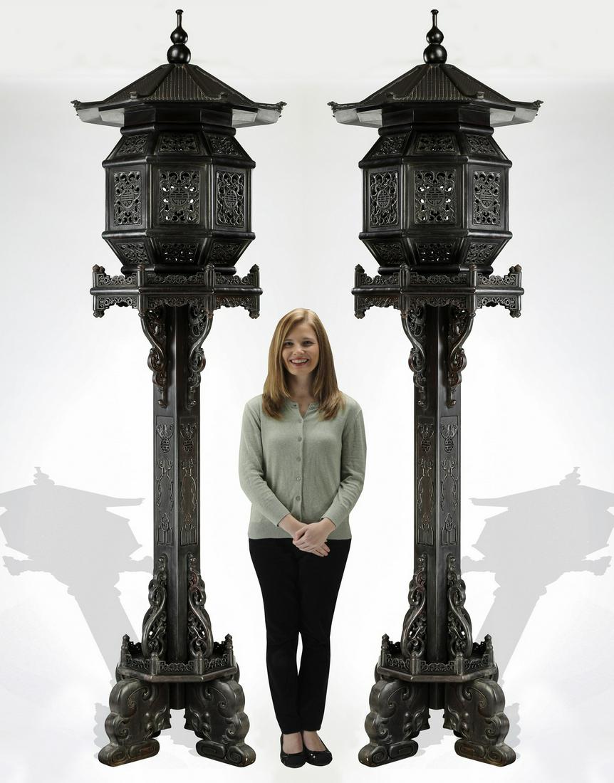 (2) Monumental Chinese ebonized hardwood lanterns: Pair of monumental Chinese ebonized hardwood lanterns, each having a pagoda form lantern with a peaked roof, above pierce carved floral panels centering Shou characters, resting on a pierce carved gal