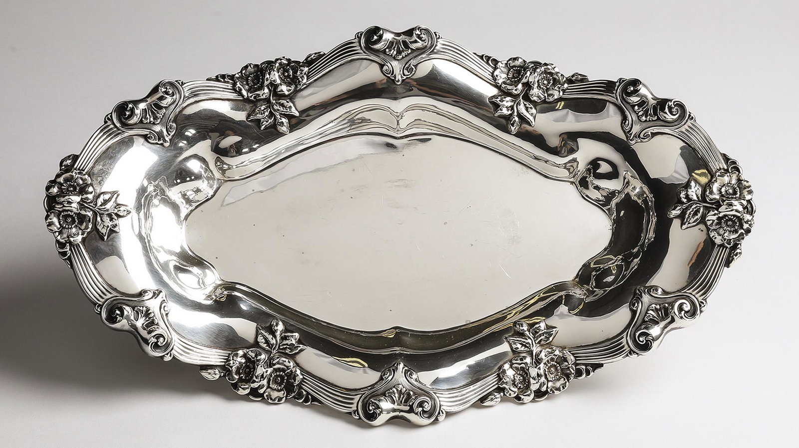 Art Nouveau sterling bread tray, 15"w: Art Nouveau sterling bread tray, having a shaped rim with repousse apple blossoms interspaced with Rococo cartouches, marked verso 'Sterling 2645,' weighing 528 grams; 2.5"h x 15.25"w x 9"d.