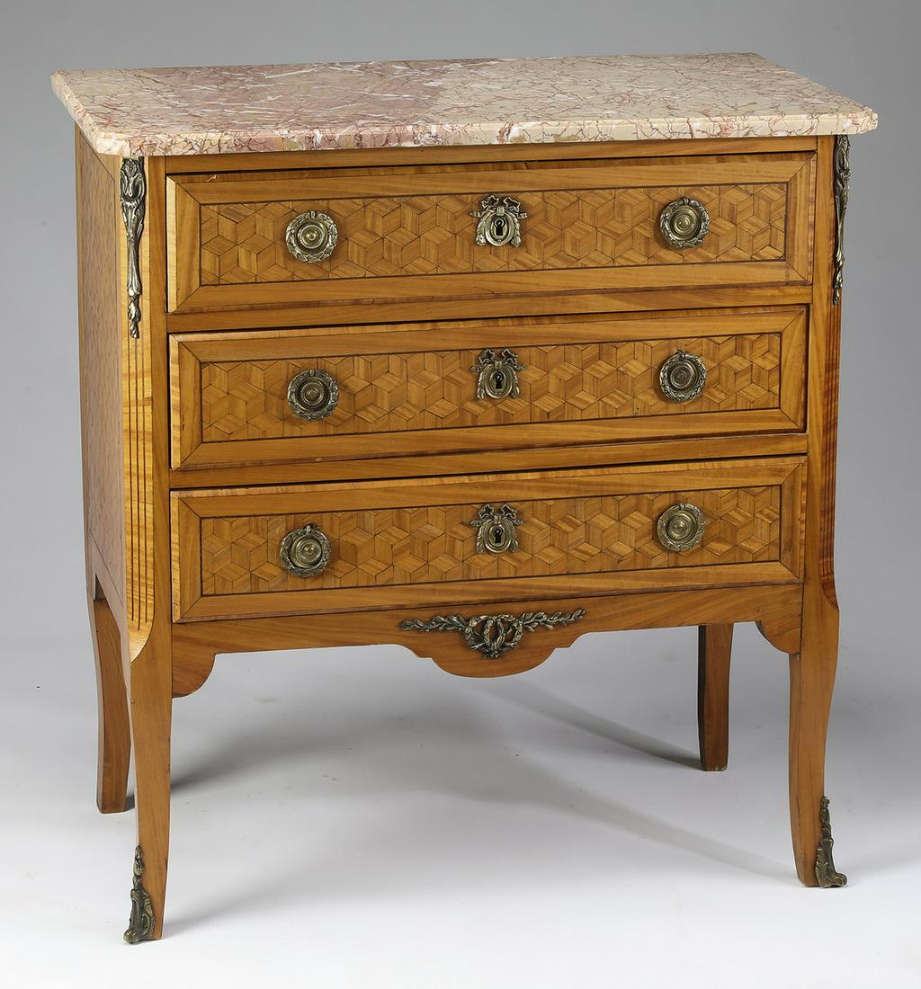 Early 20th c. parquetry inlaid marble top commode: Satinwood and marble commode in the Louis XVI taste, early 20th century, having a rectangular marble top with canted corners, surmounting a conforming cabinet with three parquetry inlaid drawers and s