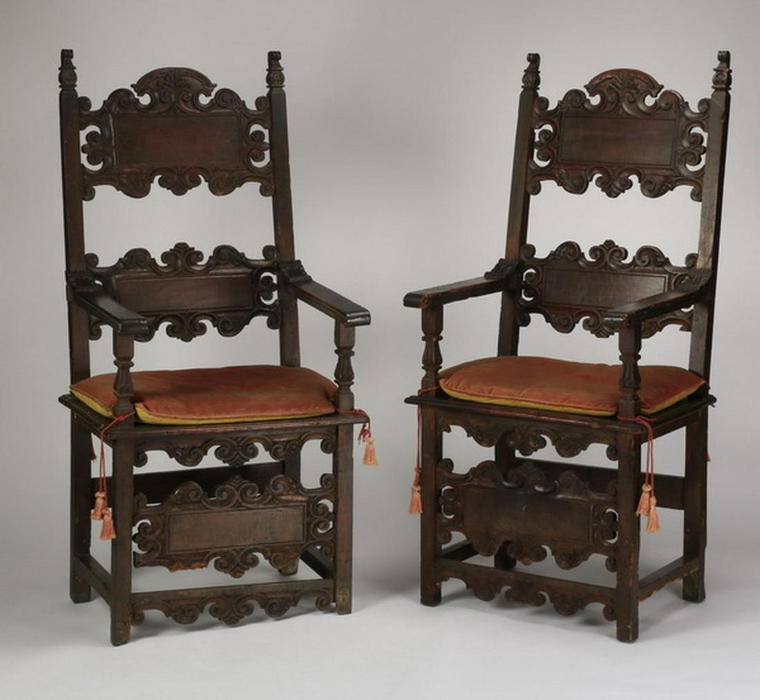 (2) 19th c. Italian carved oak armchairs: Pair of 19th century Italian Renaissance Revival style carved oak armchairs, the elaborate open backs with curved arms surmounting a square seat with loose cushions, raised on straight legs, all joine