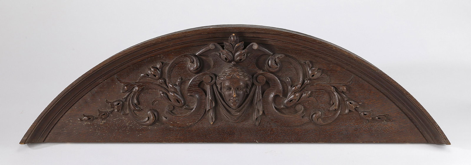 19th c. Continental relief carved walnut pediment: 19th century Continental carved Neoclassical style walnut pediment, having a female mask flanked by draperies and acanthus scrollwork, on an arched background, 11.5"h x 41"w x 2"d.