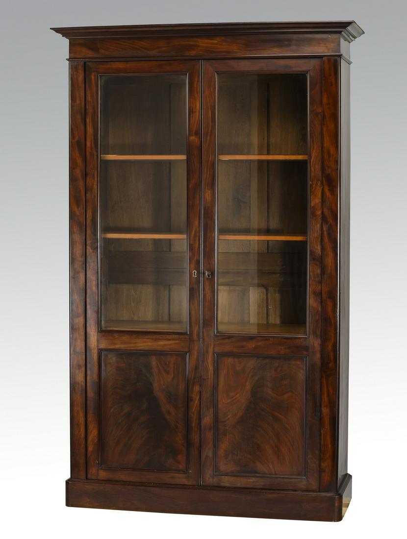 Early 20th c. French walnut bookcase, 80"h: Early 20th century French walnut bookcase, having a molded cornice above the two doors with inset glass panels opening to four adjustable wood shelves, the whole rising on a conforming plinth base, 79