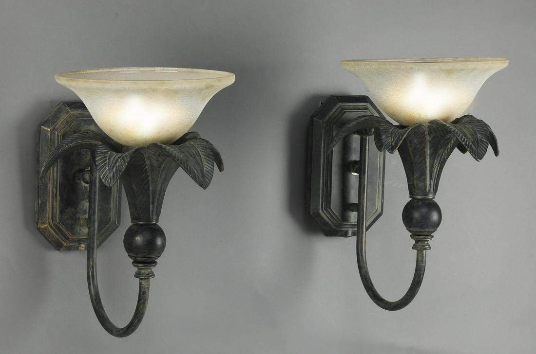 (2) Figural palm patinated iron & glass sconces: Pair of figural patinated iron and glass wall sconces, having an octagonal wall mount issuing a 'U' shaped arm supporting a palm tree form bobeche, and terminating in a glass shade, 13"h x 9"w x 14"d.