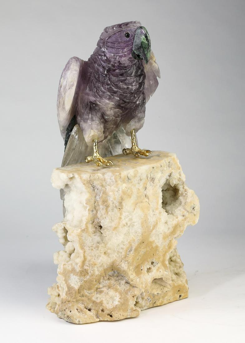 Brazilian amethyst parrot on quartz perch, 19"h: Brazilian carved amethyst parrot on a clear quartz geode perch, the parrot depicted standing on the geode having a ruby in zoisite beak and accent feathers, parrot 17.5"l; overall 18.5"h x 9.5"w x 12"