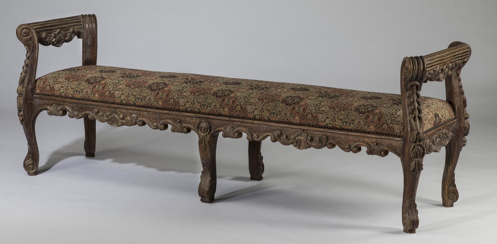 Rococo style carved bench w/ tapestry seat, 81"w: Rococo style wooden bench, 20th century, of rectangular form, having reeded scroll armrests with relief carved flowers, flanking the tapestry upholstered seat, above a carved and shaped apron, the who