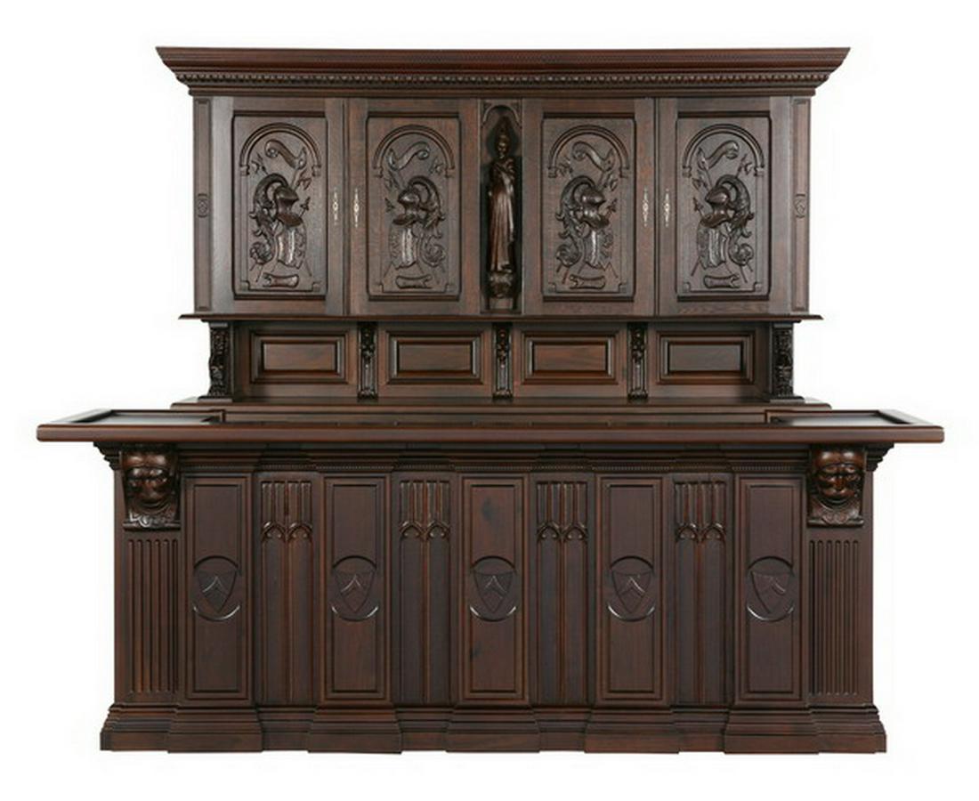 Gothic Revival carved oak front and back bar: Gothic Revival carved oak front and back bar, the back bar features an upper cabinet with door panels depicting armorial helmets flanking a central fully formed maiden surmounting storage cabinets and