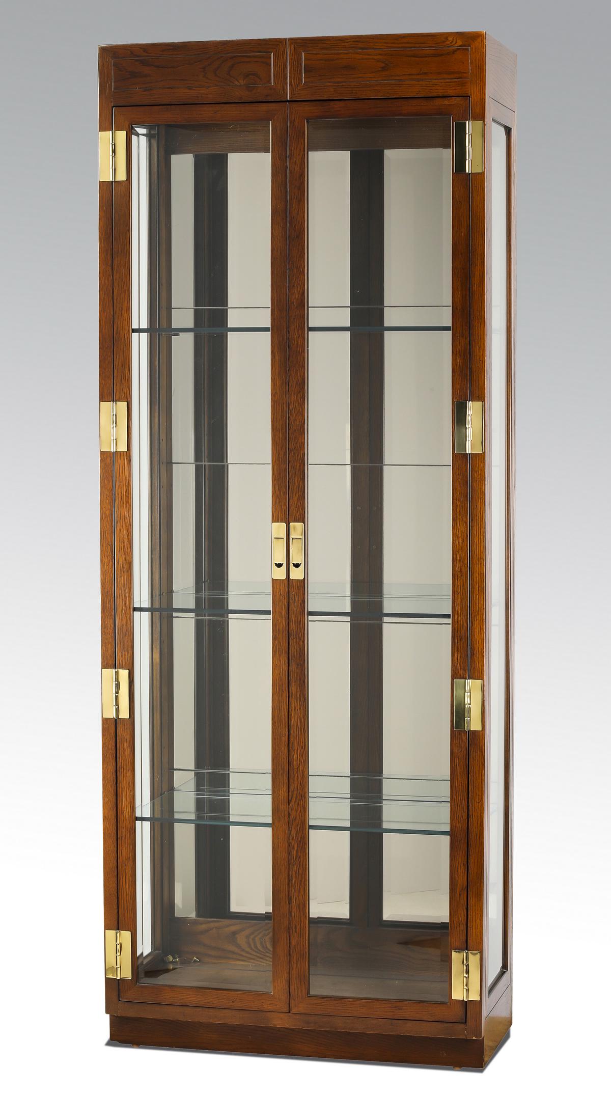 Henredon lighted campaign style display cabinet: Henredon campaign style display cabinet, the oak case having beveled glass side panels, and two beveled glass doors with brass hardware opening to a mirrored and lighted interior with three glass shel