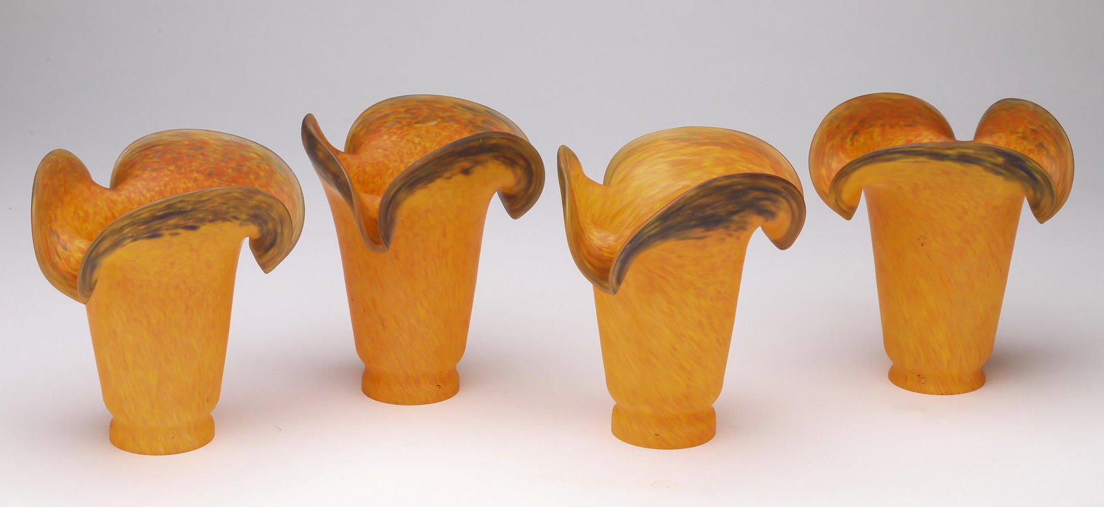 (4) Amber frit satin glass lily shades, 6.26"h: Set of four amber frit satin glass lily shades, having shaped rims with chocolate accents and tapering bodies, 6.25"h x 5.5"dia; fitter 2" dia.