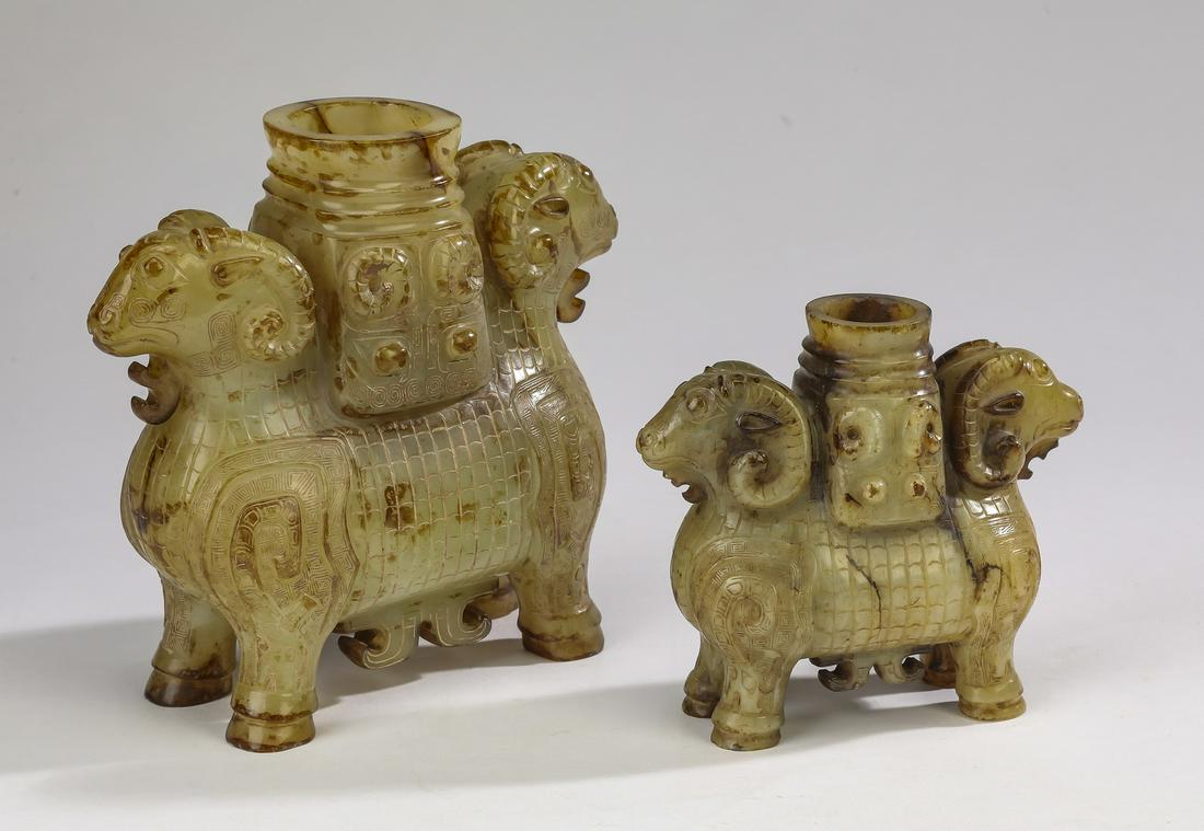 (2) Shang style Chinese jade double ram 'zuns': Two Shang style Chinese carved jade double ram 'zuns' or wine vessels, each in the shape of two addorsed rams, the heads set in opposite directions and having scrolled horns, sharing the same hollow b