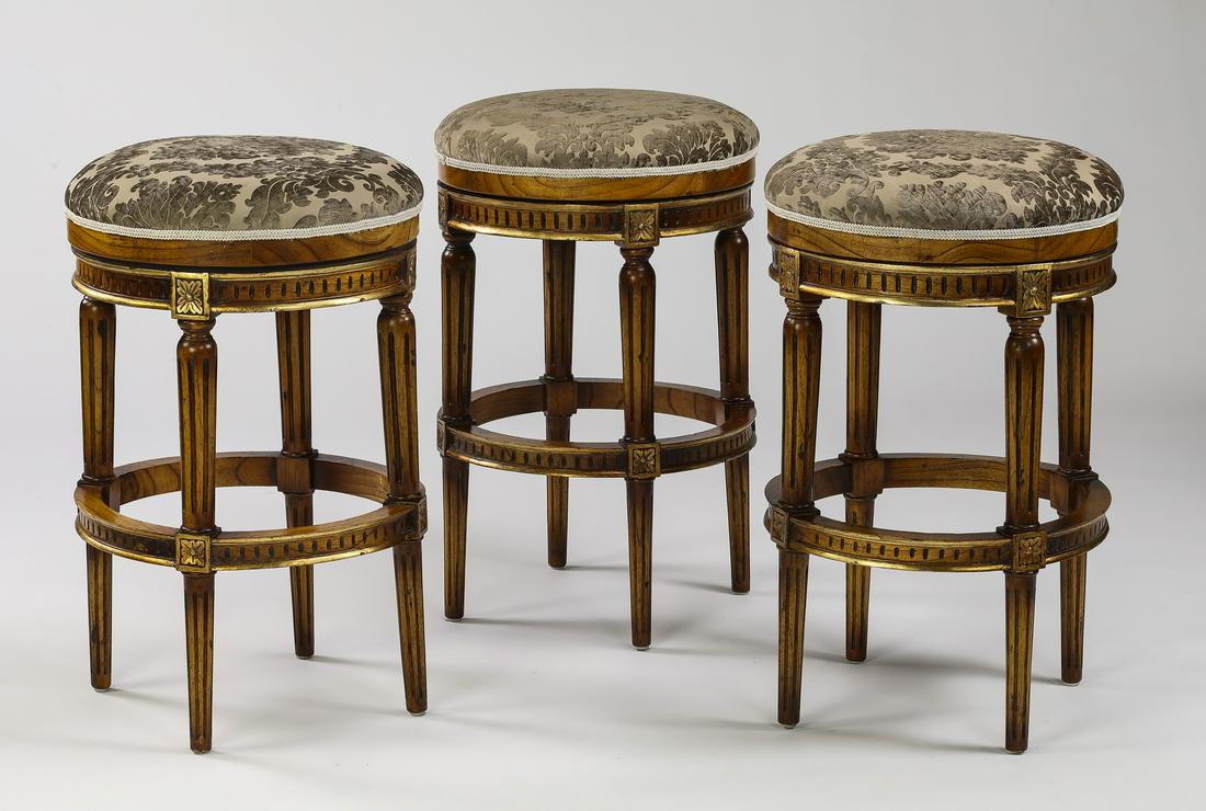 (3) Parcel gilt swivel barstools: (3) Parcel gilt swivel barstools in the Regency taste, upholstered in cut velvet, having a circular seat and dentil molding, rising on fluted tapering round legs, bar-height measuring 31"h x 19"d.