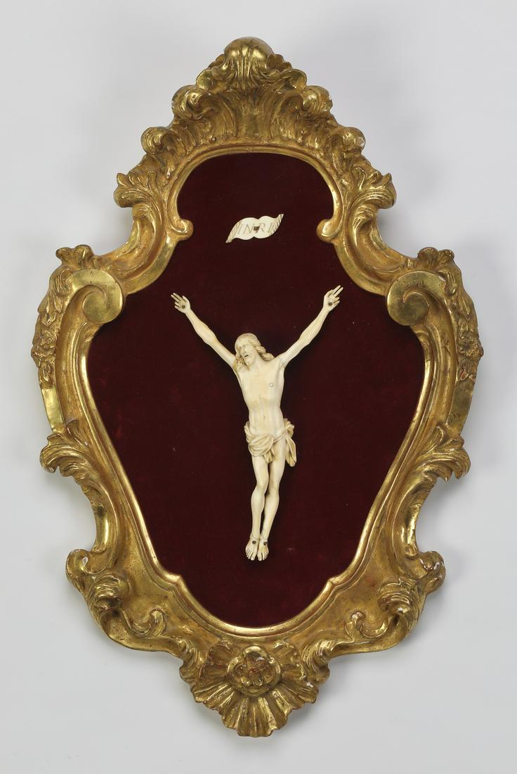 19th c. giltwood plaque with carved corpus: 19th century plaque having a carved corpus on a red velvet ground, in a Rococo style giltwood frame of cartouche shape; the corpus 7.5"h, overall size including frame, 20"h x 12.5"w x 4"d.