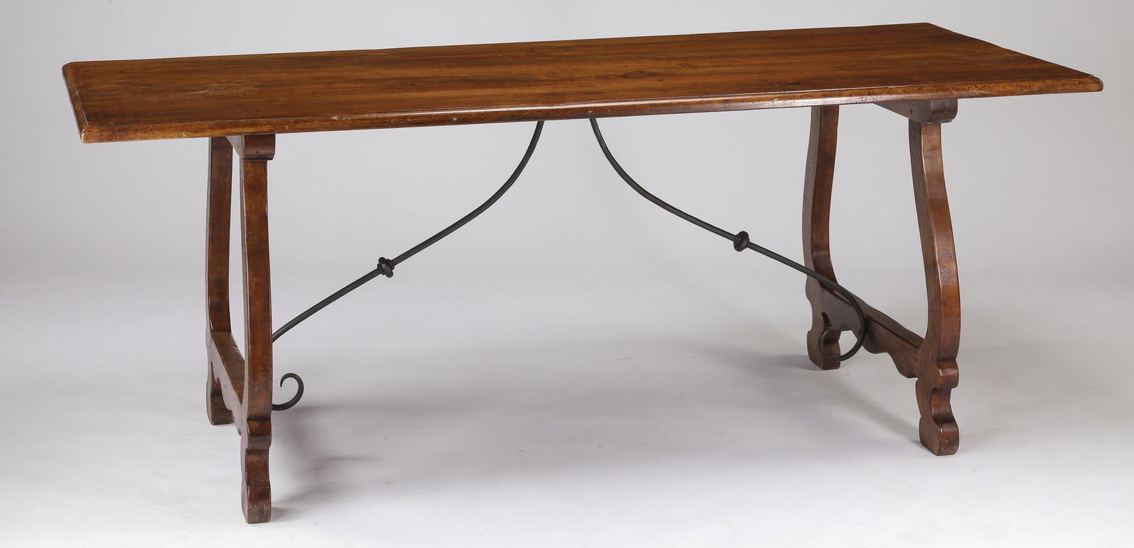 Early 20th c French Baroque style walnut table: French walnut and iron trestle table in the Baroque taste, early 20th century, having a rectangular top surmounting a pair of lyre shaped trestle bases connected by a scrolling iron brace, 31"h x 78"w