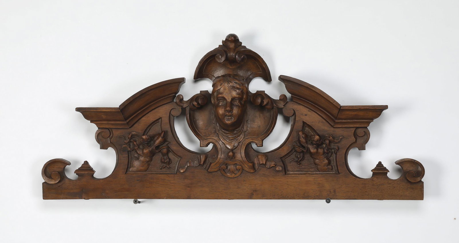 19th c. Continental carved architectural pediment: 19th century Continental carved walnut architectural pediment, having a putto mask centered by acanthus scrollwork above garlands and dragon masks, 12.5"h x 33"w x 3"d.