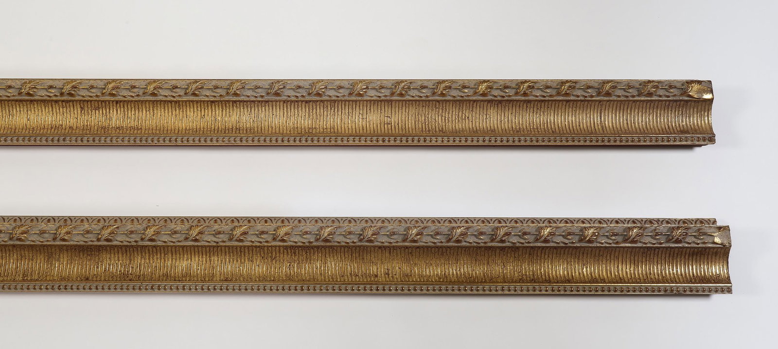 (2) Italian carved and gilt decorative moldings, 118": Pair of Italian carved and gilt decorative moldings, having fluted, acanthus, and egg and dart details, each measuring 4.5"h x 118.5"l x 2.5"d.