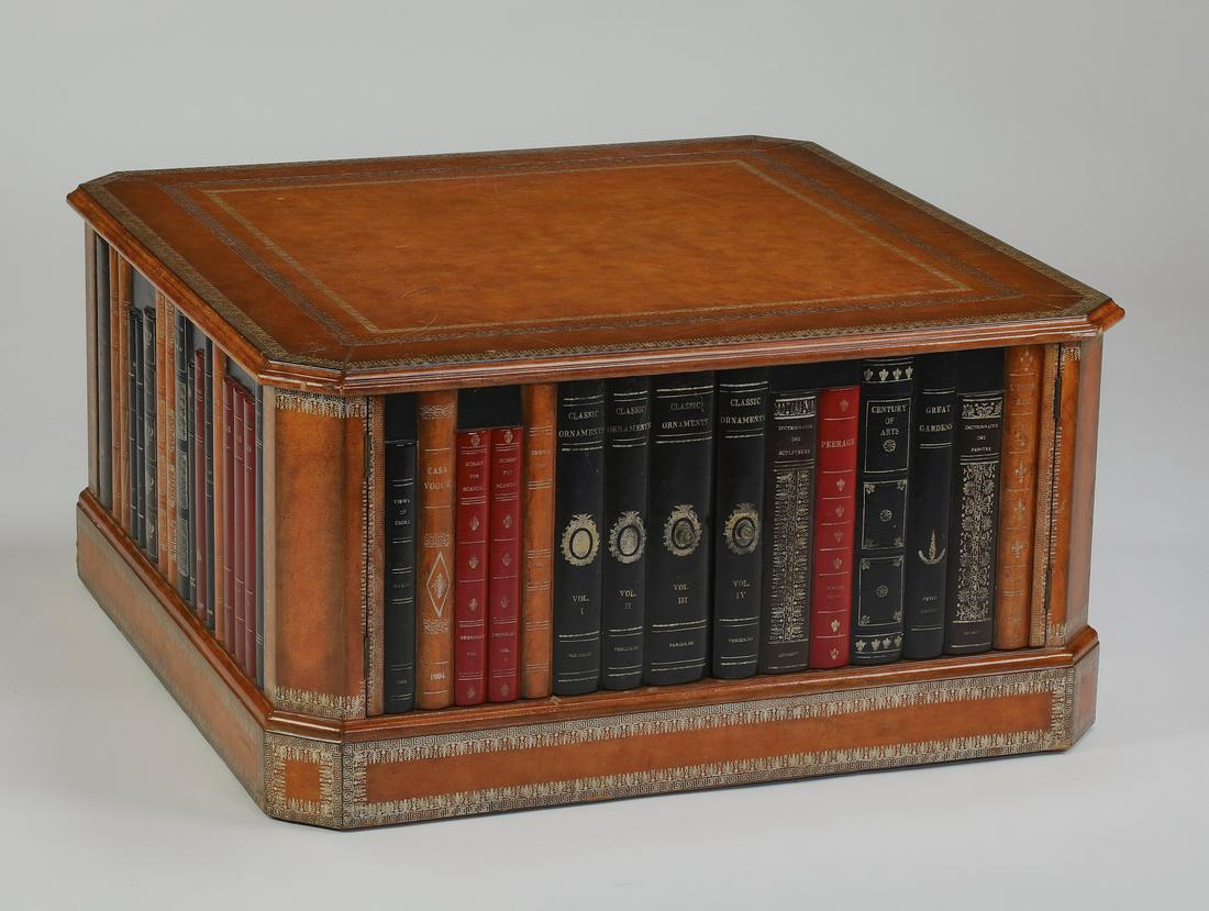 Maitland Smith style book cocktail table w/ storage: Maitland Smith style leather covered 'bookshelf' cocktail table, having a leather covered square top with decked corners, above a wide apron with a row of faux books, on two sides the row of books ope