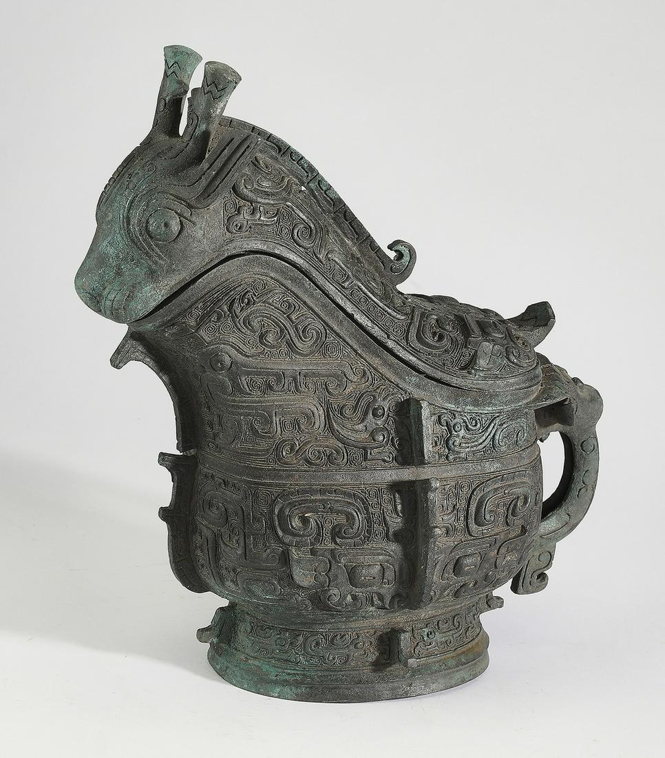 Shang style Chinese figural bronze 'guang,' 11"h: Shang style Chinese figural bronze wine server or 'guang,' in the form of a fantastical beast, the spout molded as a horned beast head, above a reverse 'S' shaped body decorated with taotie masks, the